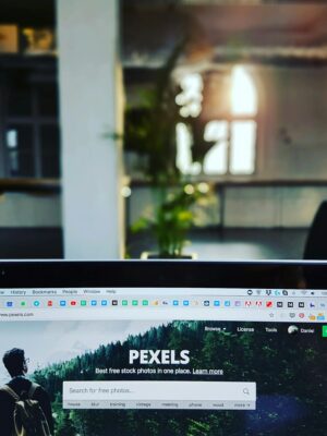 A close-up of a laptop displaying the Pexels website in a sunlit, modern office.
